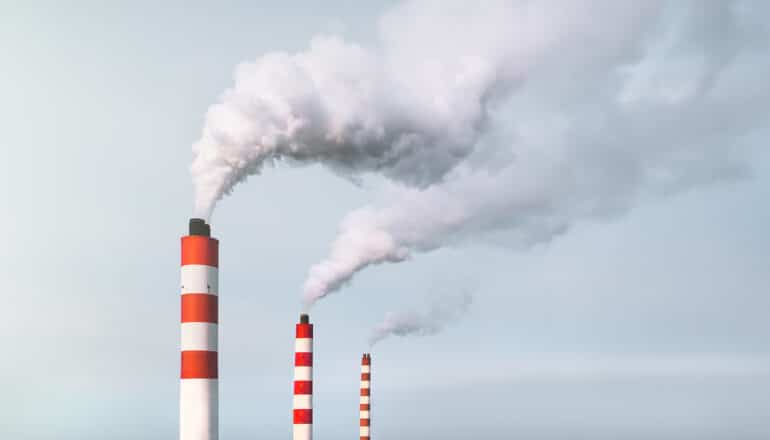Three smokestacks pump smoke into the air.