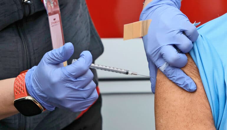 A nurse gives a person a COVID booster shot in their arm.
