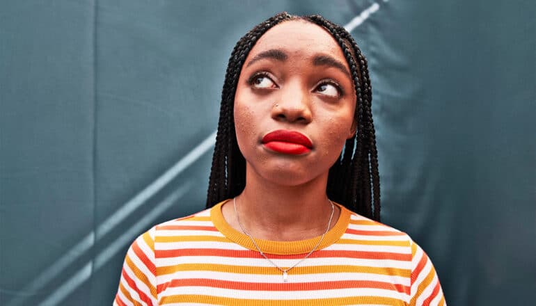 A young woman looks upwards with a curious expression.