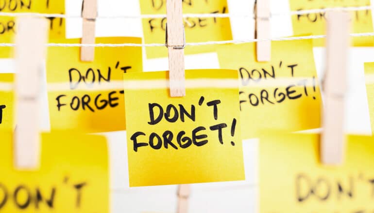 Yellow post it notes hanging from clothespins on string with the words