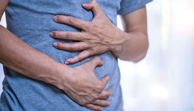 A man clutches his stomach in pain.