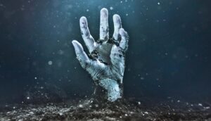A zombie hand emerges from soil and reaches upward.