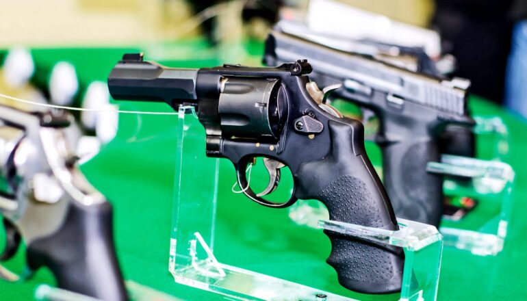 A row of guns for sale against a green background.