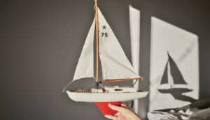 A young child holds up a toy sailboat as it casts a shadow on the far wall.
