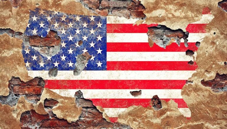 An American flag in the shape of the United States painted on an old, decaying wall.
