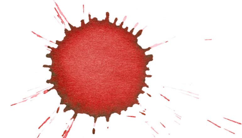 A red droplet stain on a white surface.
