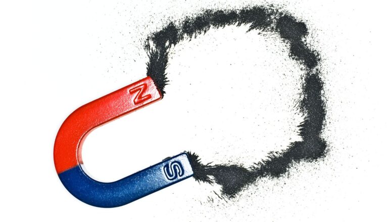 A blue and red magnet on a white background with magnetic dust.
