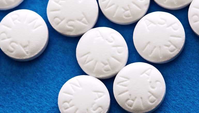 Several white aspirin pills on a blue surface.