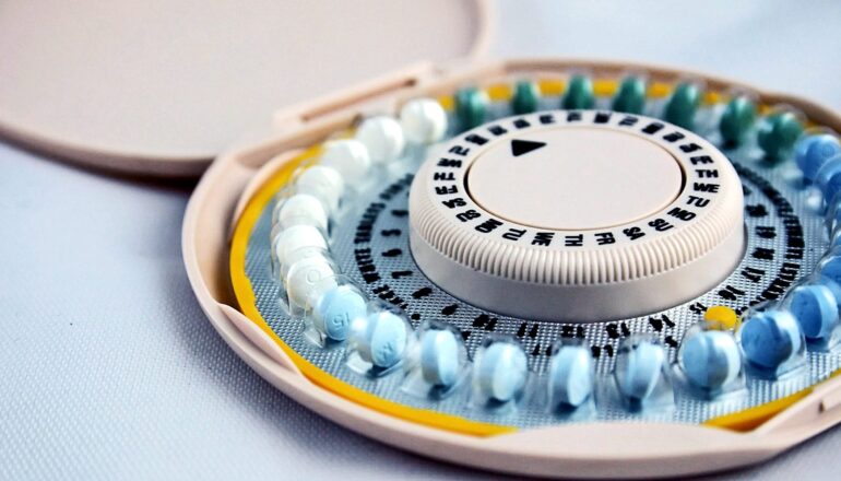 A plastic pack of birth control pills sits on a light blue surface.