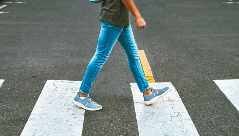 A young man walks across a crosswalk.