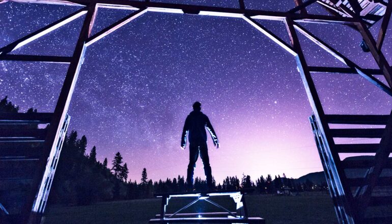 A person looks up a the night sky and sees many many stars.
