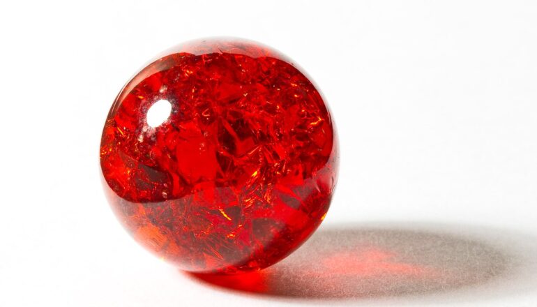 A red marble on a white surface.