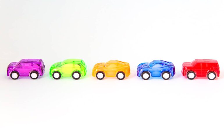 Small, colorful toy cars in a row on a white surface.