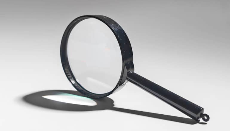 A magnifying glass sits on its side on a gray surface.