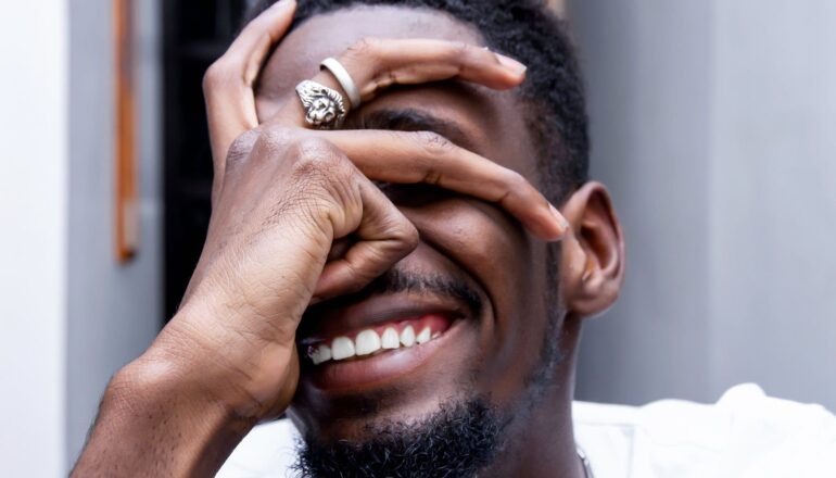A man smiles and covers his face in embarrassment.