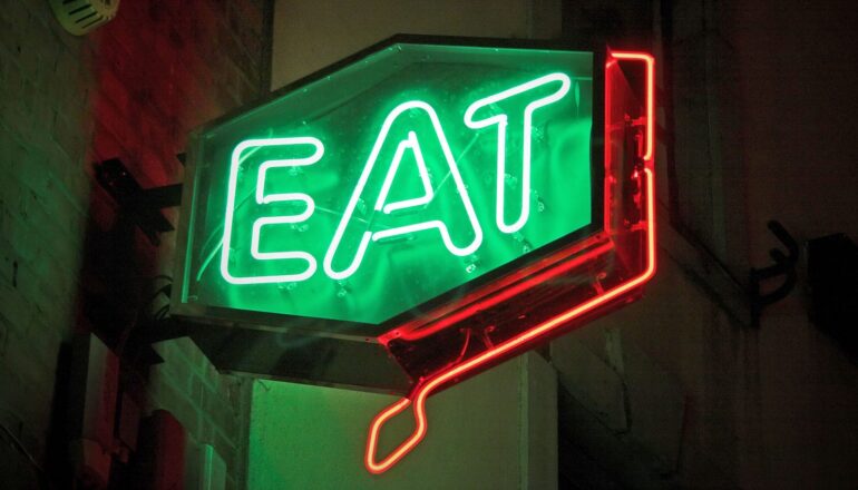 A neon sign reads "eat" in green letters.