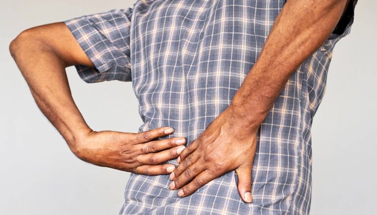 A man grasps at his lower back in pain.