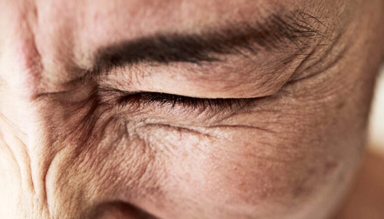 A close up of a person grimacing in pain.