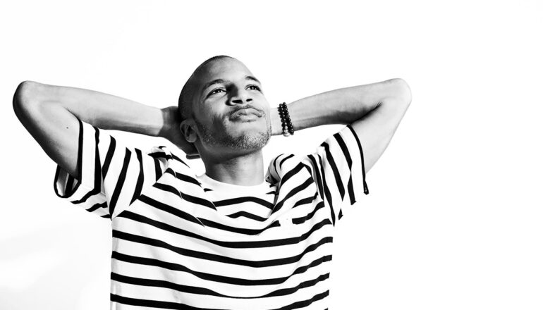 A young man puts his arms behind his head and looks up into the distance.