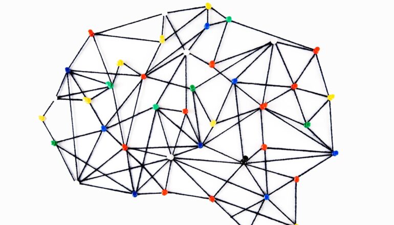 Colorful pins connected by string form the shape of a human brain.
