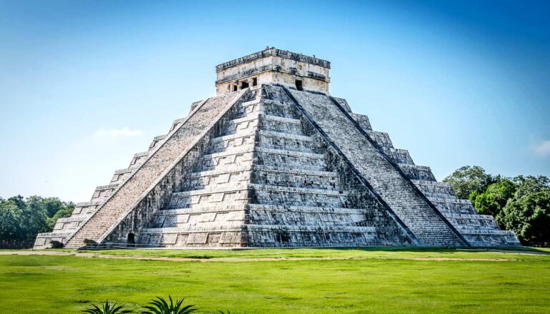 A Maya temple in a grassy field.