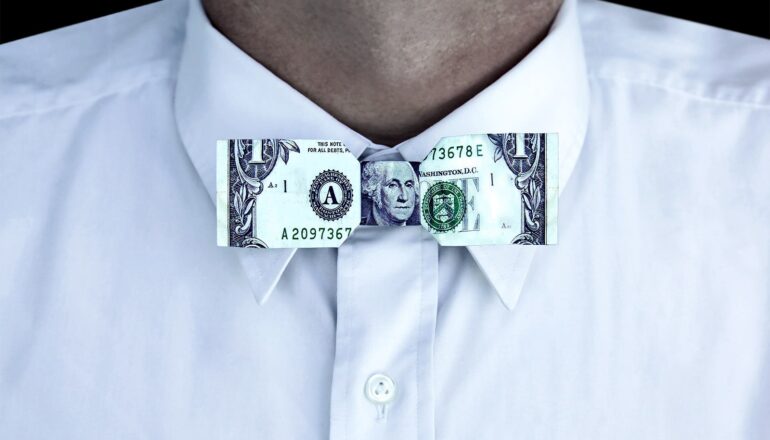 A man wearing a bowtie made of a dollar bill.