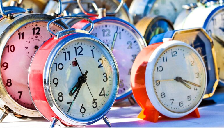 A group of vintage alarm clocks on a table.