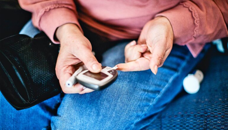A woman checks her blood sugar using a handheld device.