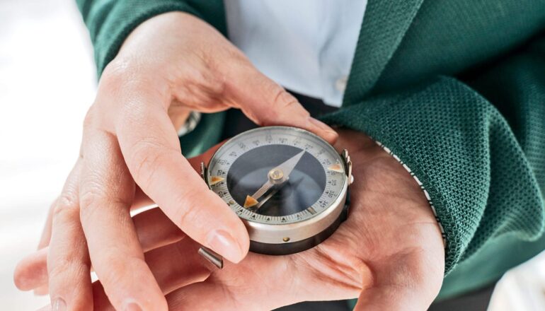 A man holds a compass in the palm of one hand.