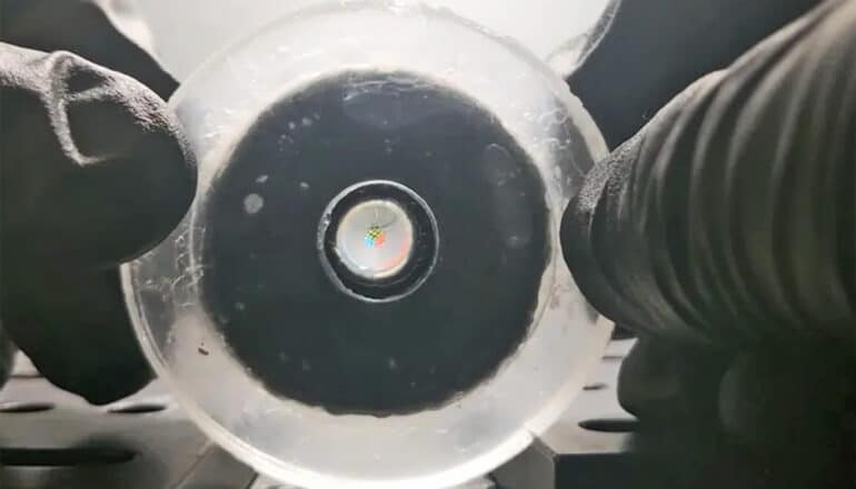 A researcher wearing gloves holds the lens up to the camera.