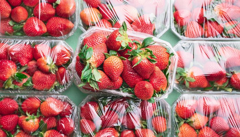 Several packages of strawberries covered in plastic.