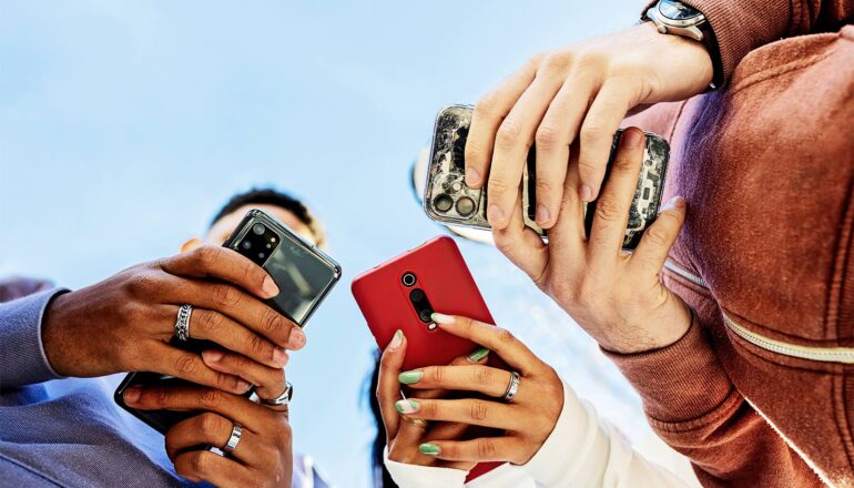 A group of three people look down at their phones.