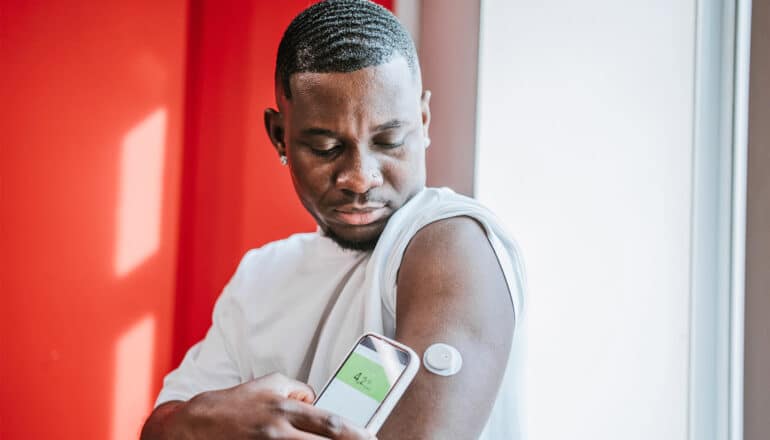 A man checks his continuous glucose monitor with his smartphone.