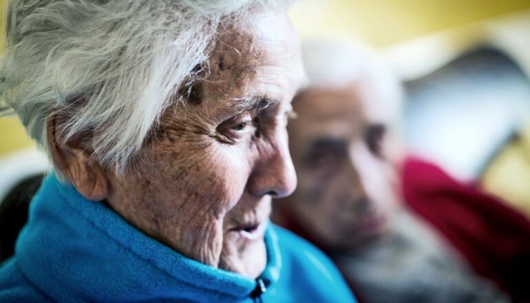 An older woman and man sit next to each other on a couch.