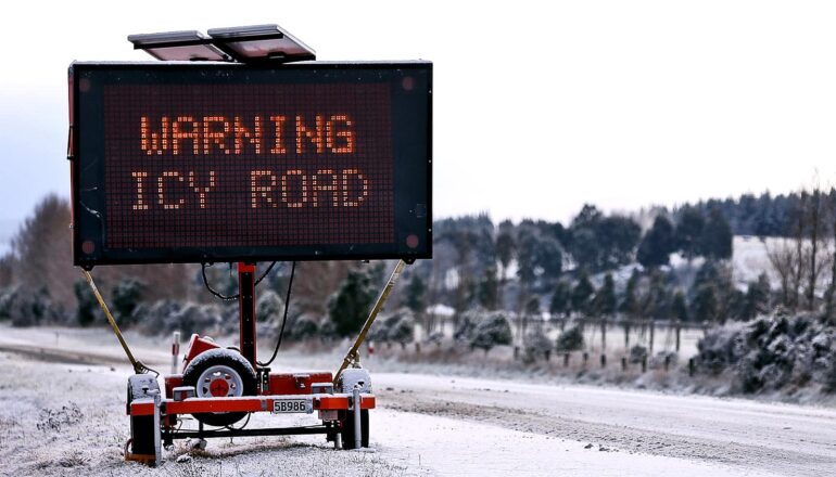 A sign at a roadside reads "Warning Icy Road."