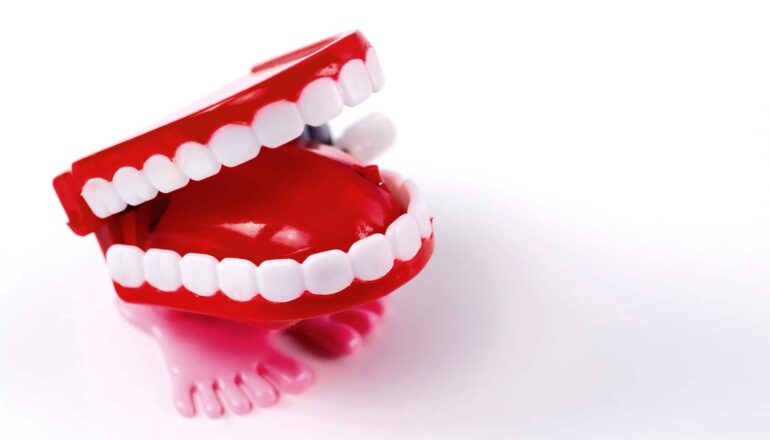 A wind-up toy set of teeth with feet on a white background.