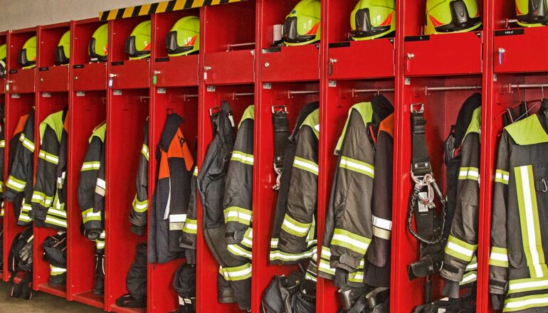 Firefighter gear in cubbies in a row.