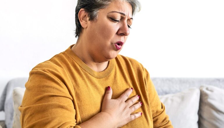 A woman holds her chest as she struggles to catch her breath.