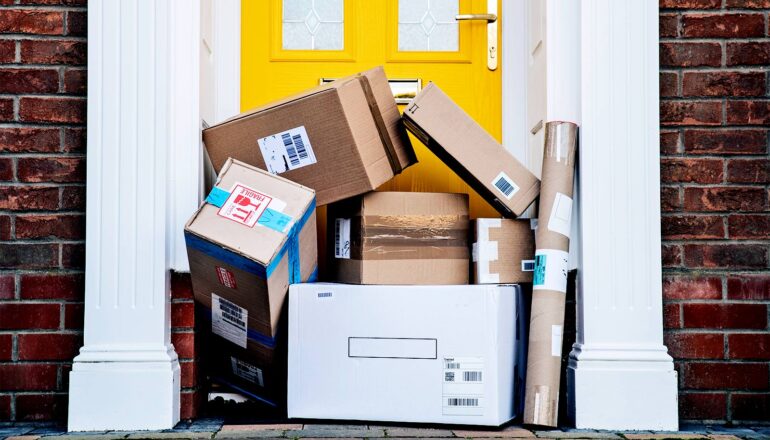A haphazard pile of boxes sits in front of a house door.