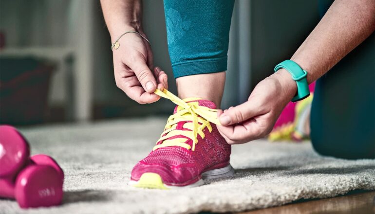 A person ties up running shoes inside before going out for a run.