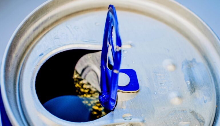 A close-up of a the top of a can of energy drink with a blue tab.