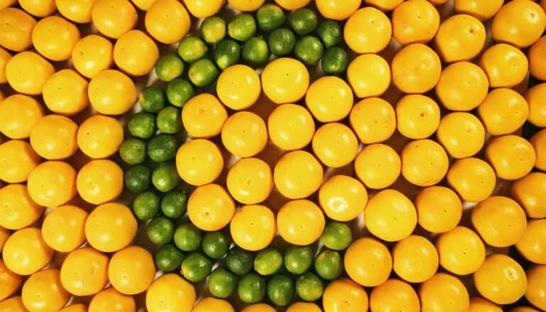 A letter c made with limes sitting amongst oranges.