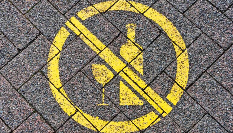 A sign that shows a bottle of wine and a glass with a line through them.