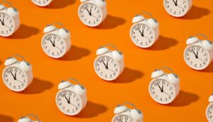 Rows of white alarm clocks on an orange background.