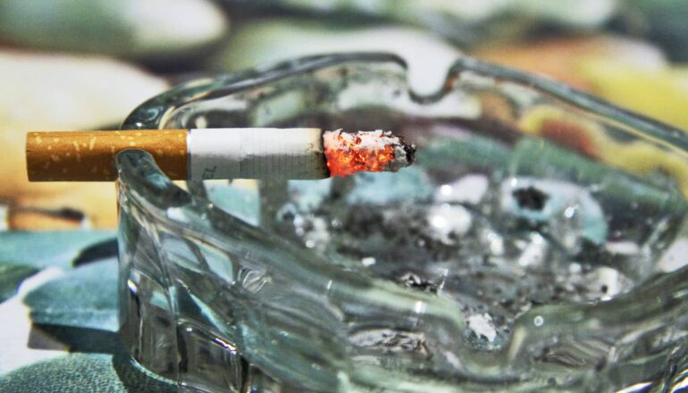 A lit cigarette in an ashtray.