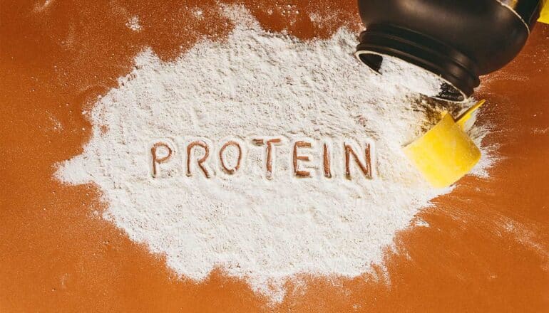 The word "protein" spelled out in a pile of protein powder.