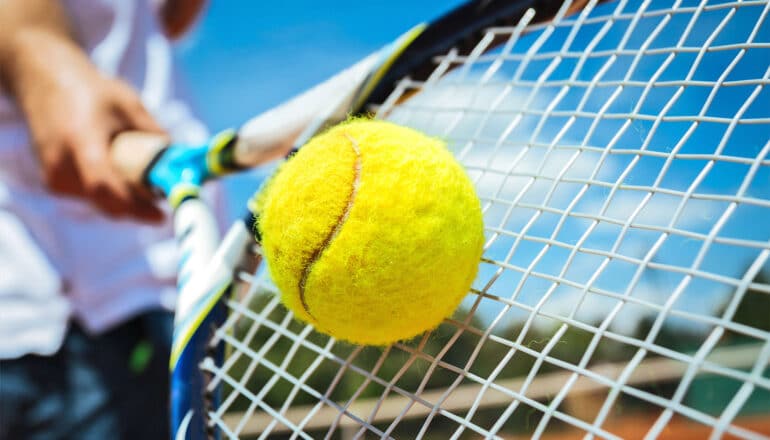 A person hits a tennis ball with a racket.