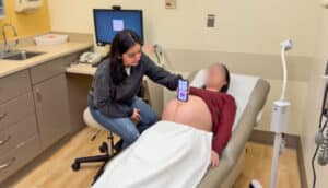 A researcher uses the at-home fetal heart monitor app on a phone with a pregnant participant.