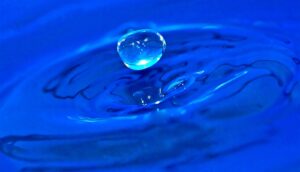A droplet falls into blue water.