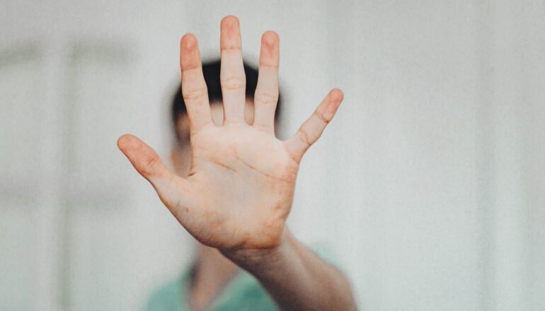 A person holds their palm out to say "stop."